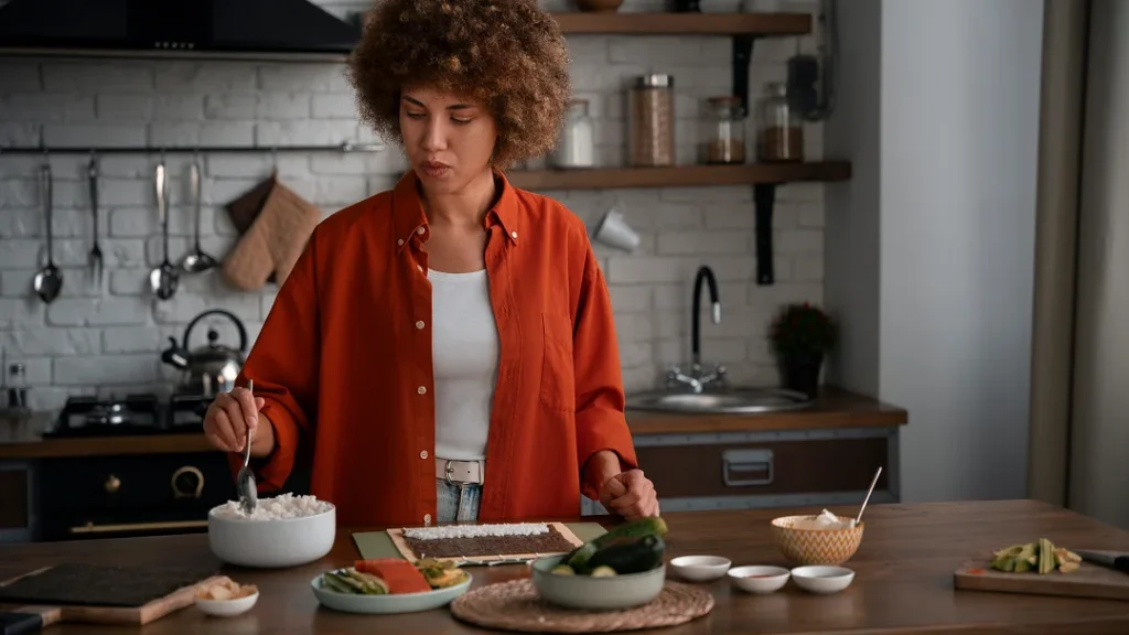 Une femme prépare des aliments dans une cuisine moderne, illustrant les tendances culinaires de 2025.