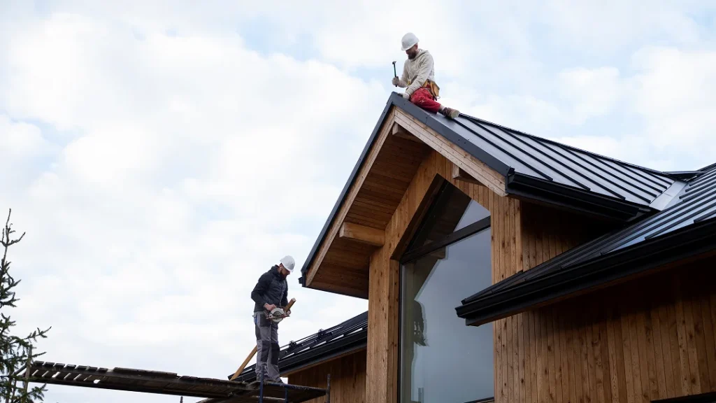 Deux hommes sur le toit d'une maison, travaillant sur la rénovation de l'extérieur.