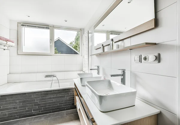 Salle de bain rénovée avec deux lavabos modernes et une baignoire spacieuse.