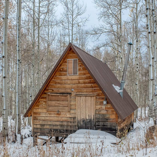 Maison moderne avec un toit à pignon sombre située sur une dune herbeuse près du rivage.